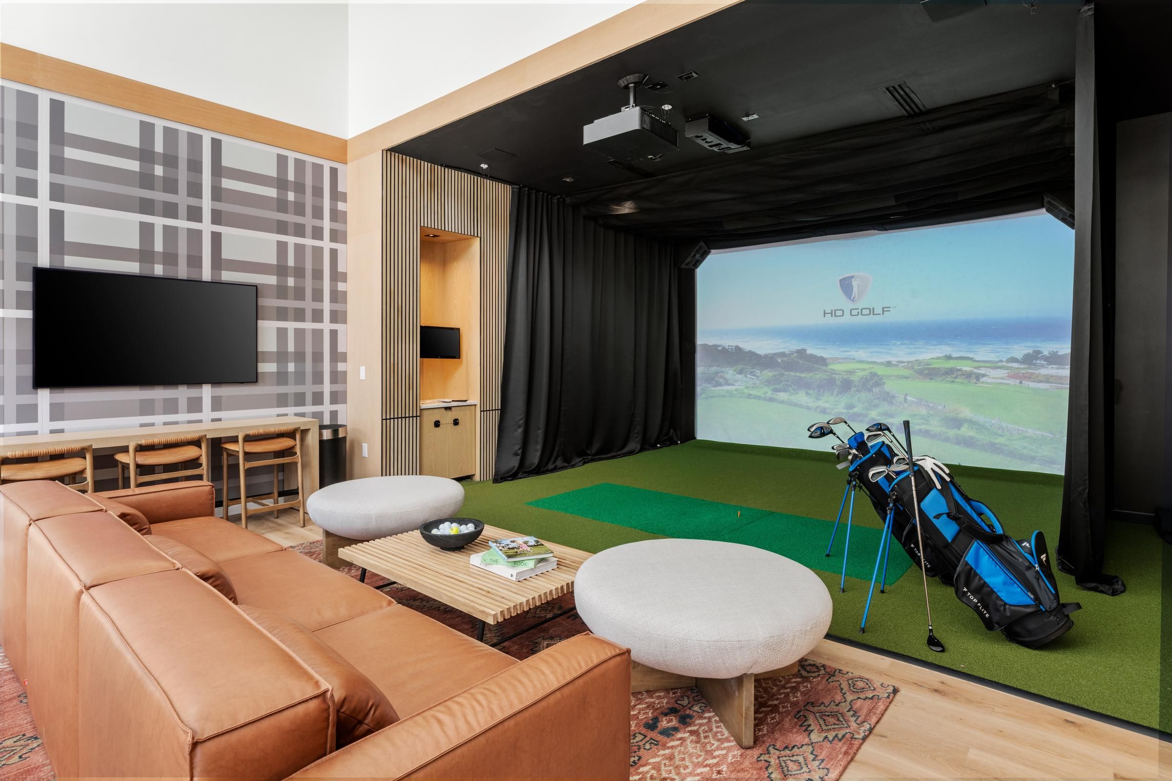The Oslo with a golf simulator, leather sofa, TV, and golf bags on artificial turf.