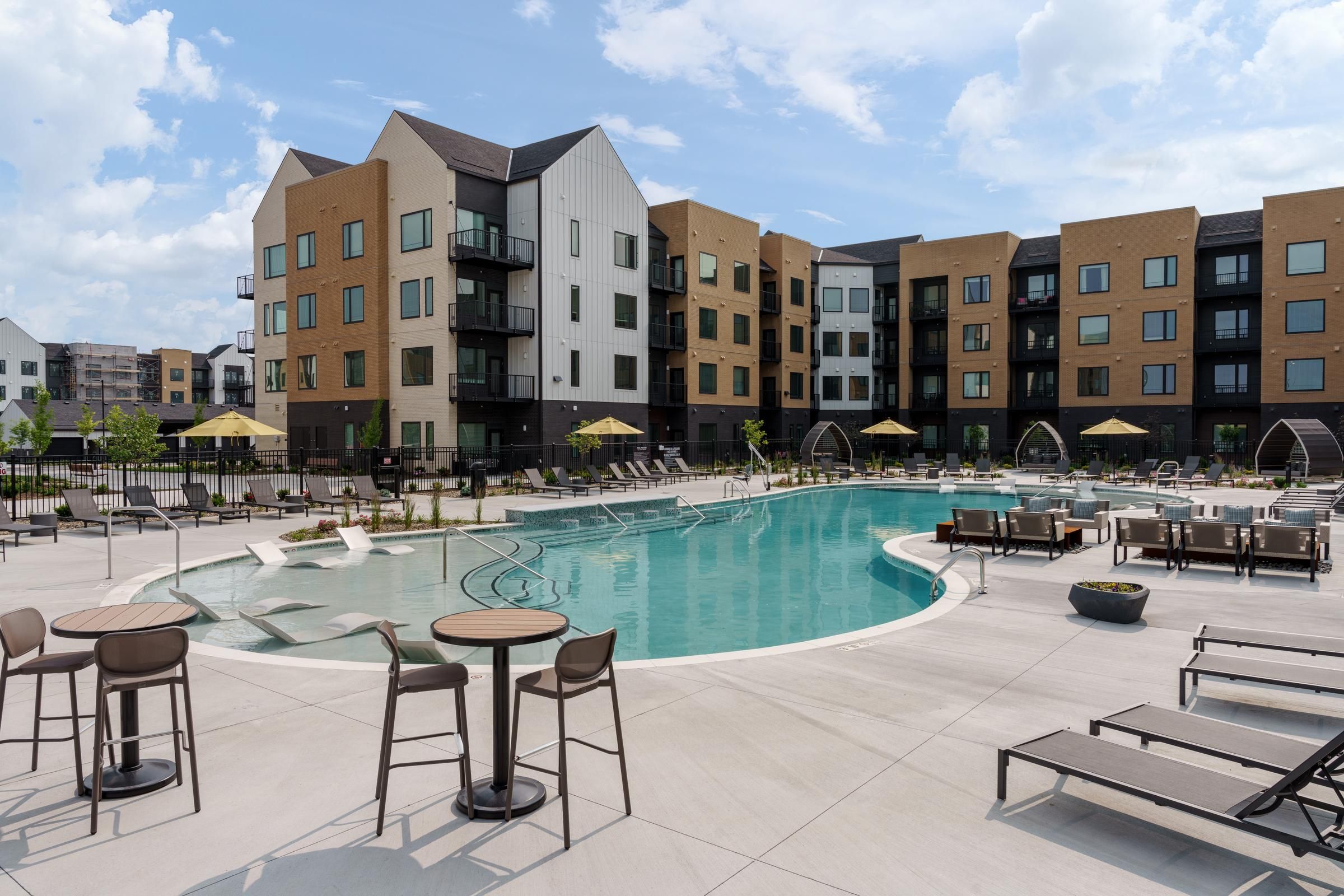 The Oslo with outdoor pool, lounge chairs, tables, and umbrellas under a partly cloudy sky.