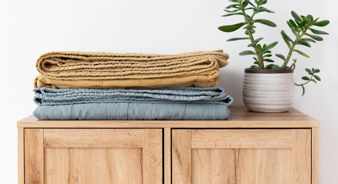 The Oslo A neatly arranged stack of towels resting on a wooden cabinet, showcasing a blend of colors and textures.