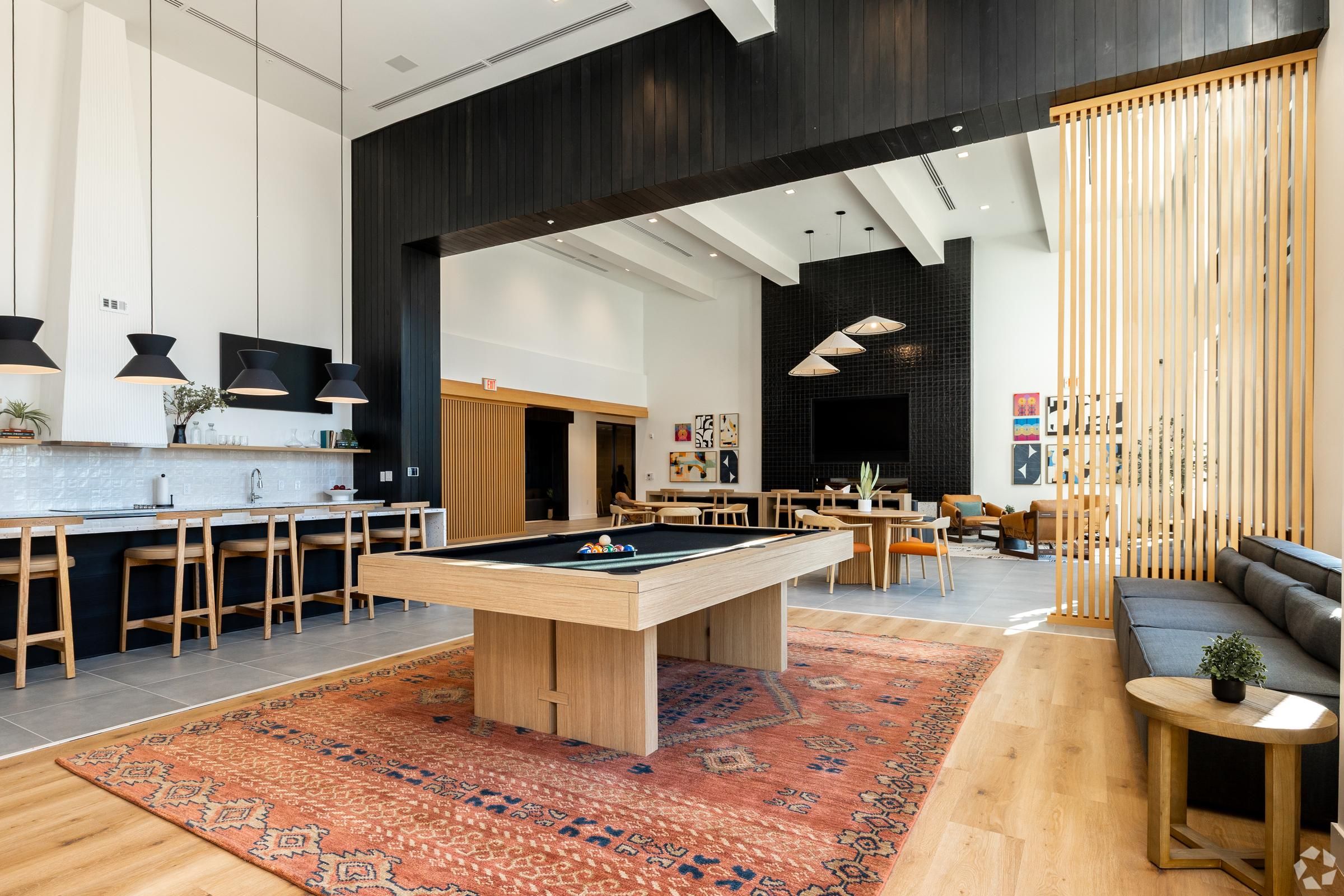 The Oslo with a pool table, kitchen area, bar stools, and stylish seating on a patterned rug.