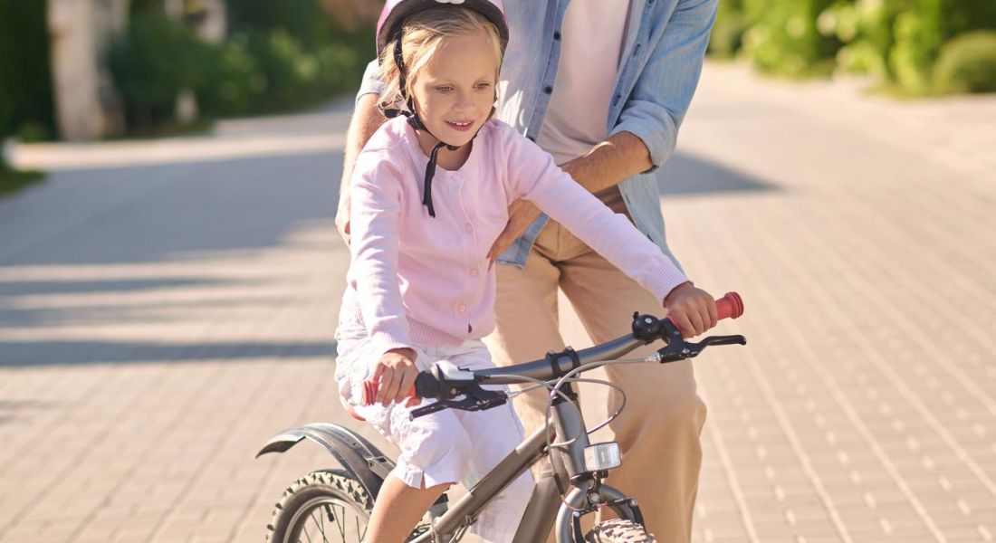 The Oslo A man and a young girl joyfully riding a bicycle together, enjoying a sunny day outdoors.
