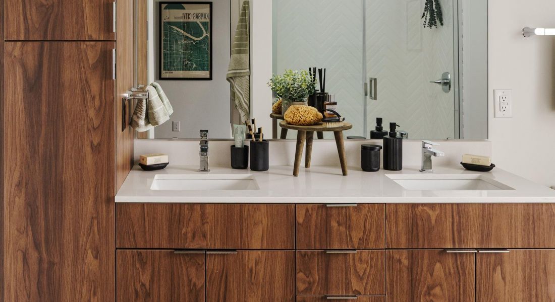 Modern bathroom with wooden cabinetry, large mirror, and various toiletries arranged neatly on the counter.